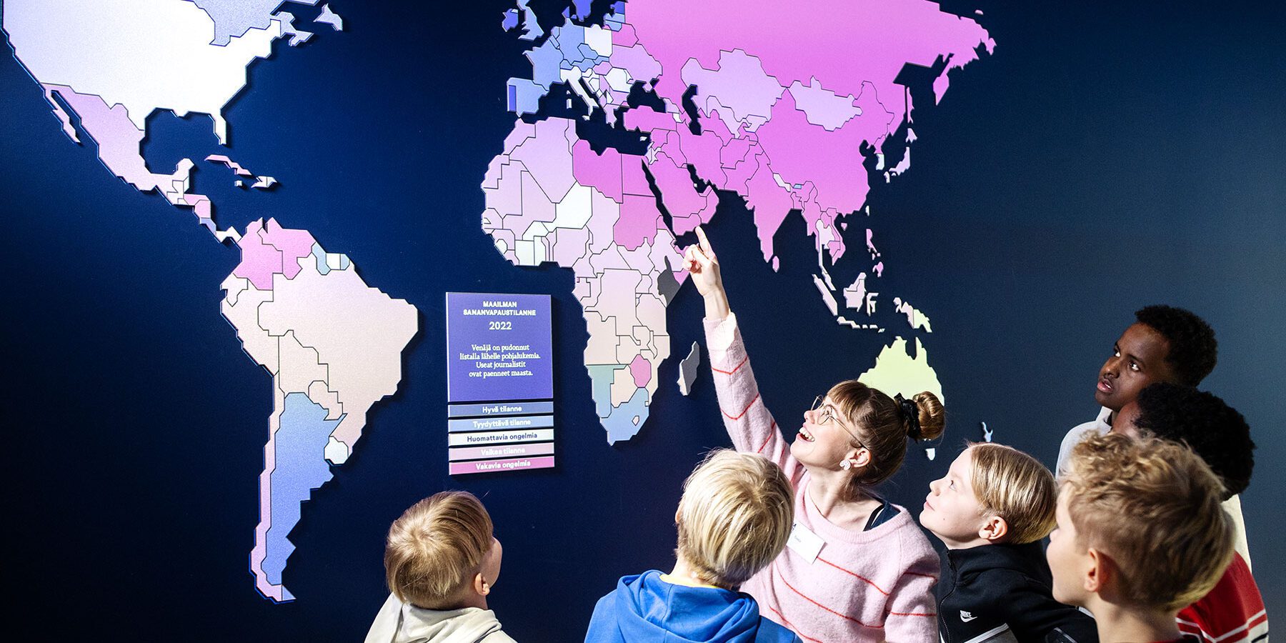 Museon opas esittelee lapsille seinällä olevaa karttaa.