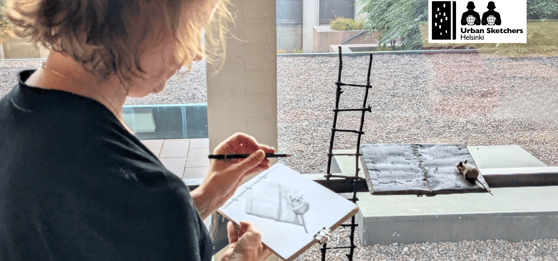 Ihminen piirtää paperille pientä veistosta mallista.