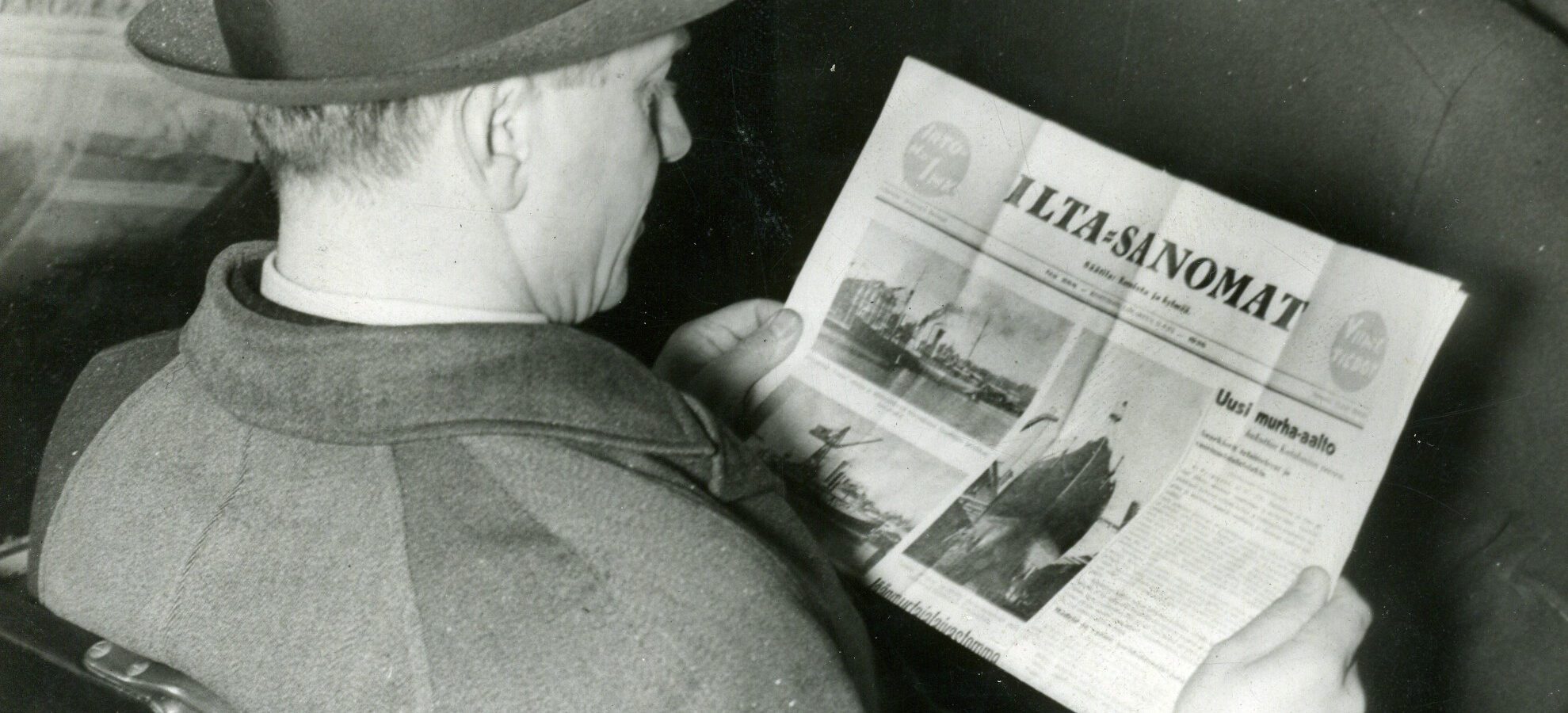 Lierihattupäinen mies istumassa, kädessään sanomalehti Ilta-Sanomat.